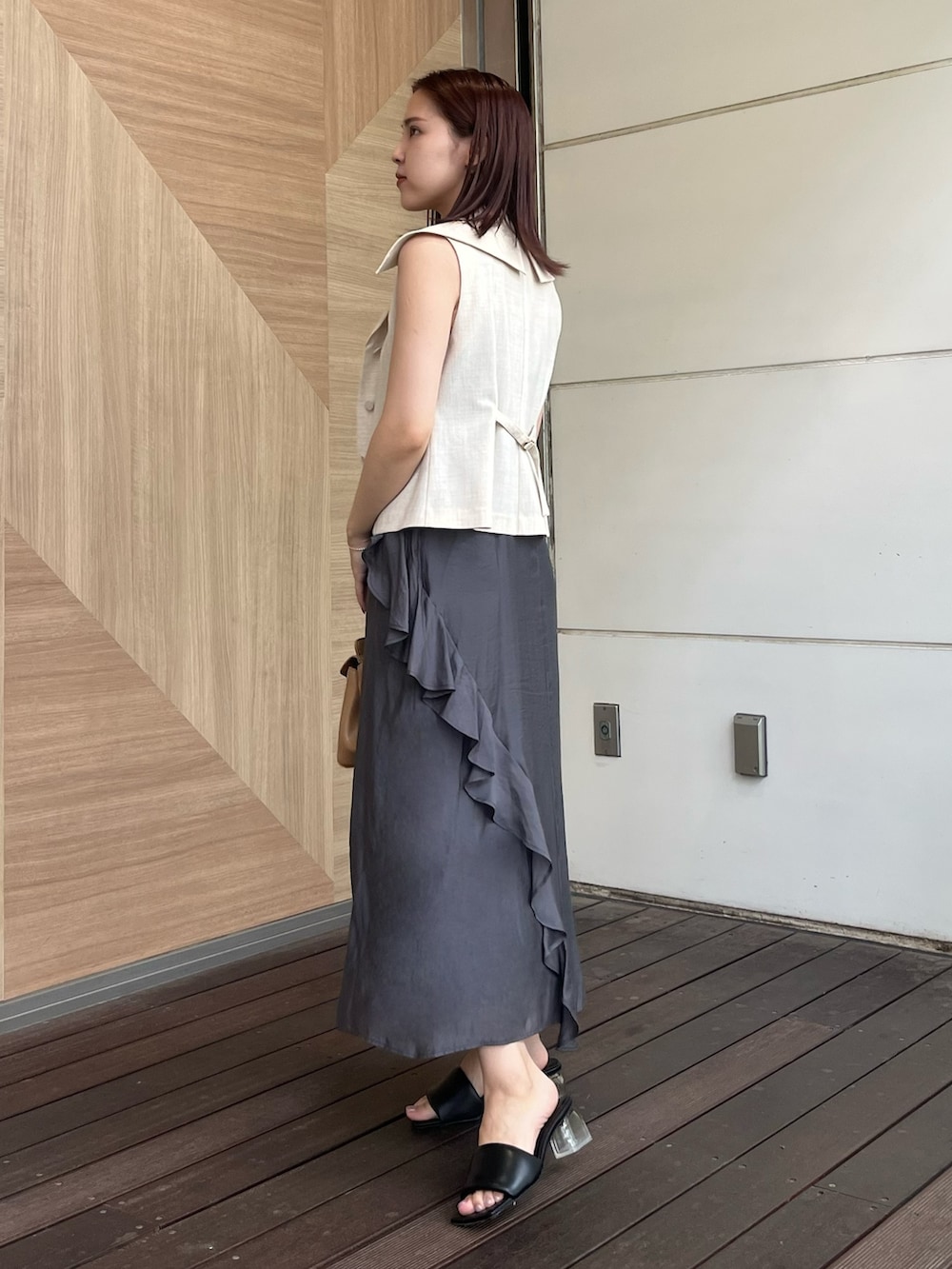 ホワイト系のベスト、グレー系のワンピース、ブラウン系のハンドバッグを着用したレディースの夏コーディネートの2枚目の写真