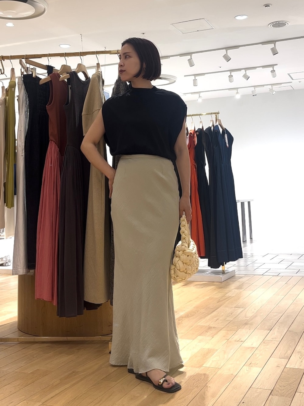 グリーン系のスカート、ブラック系のニット/セーター、ブラック系のサンダルを着用したレディースの夏コーディネートの2枚目の写真