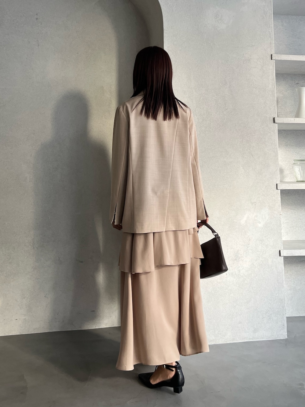 ベージュ系のテーラードジャケット、ベージュ系のワンピース、ブラウン系のハンドバッグを着用したレディースの冬コーディネートの3枚目の写真