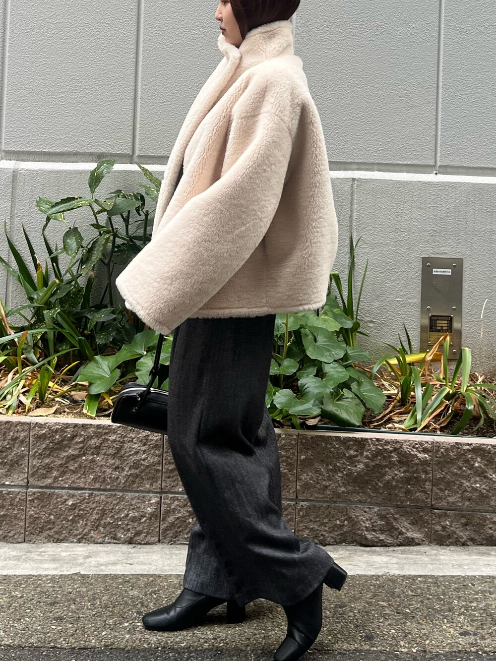 ホワイト系のムートンコート、グレー系のその他パンツ、グリーン系のニット/セーターを着用したレディースの冬コーディネートの5枚目の写真