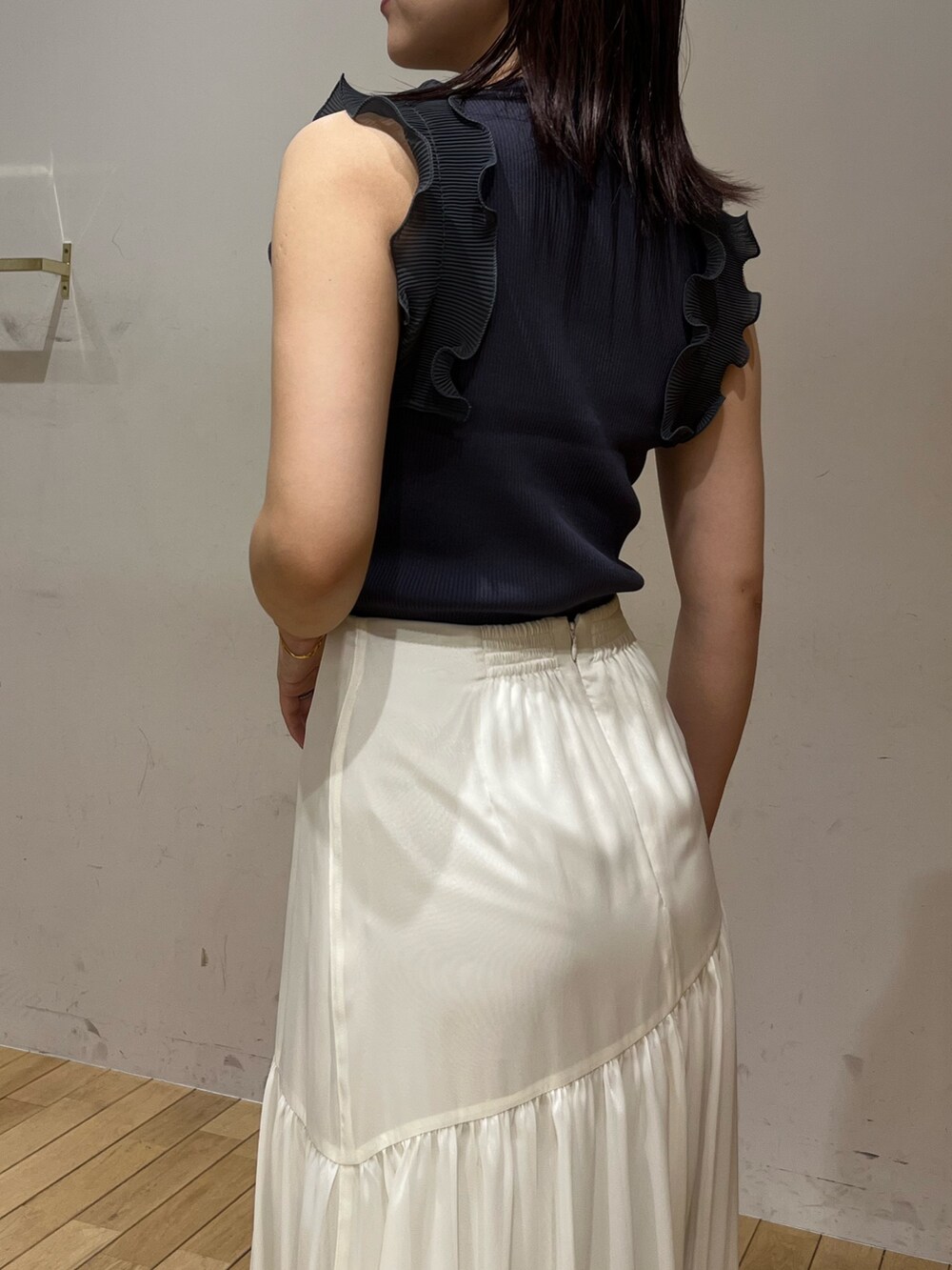 ブラック系のスニーカー、ホワイト系のスカート、グレー系のニット/セーターを着用したレディースの夏コーディネートの6枚目の写真