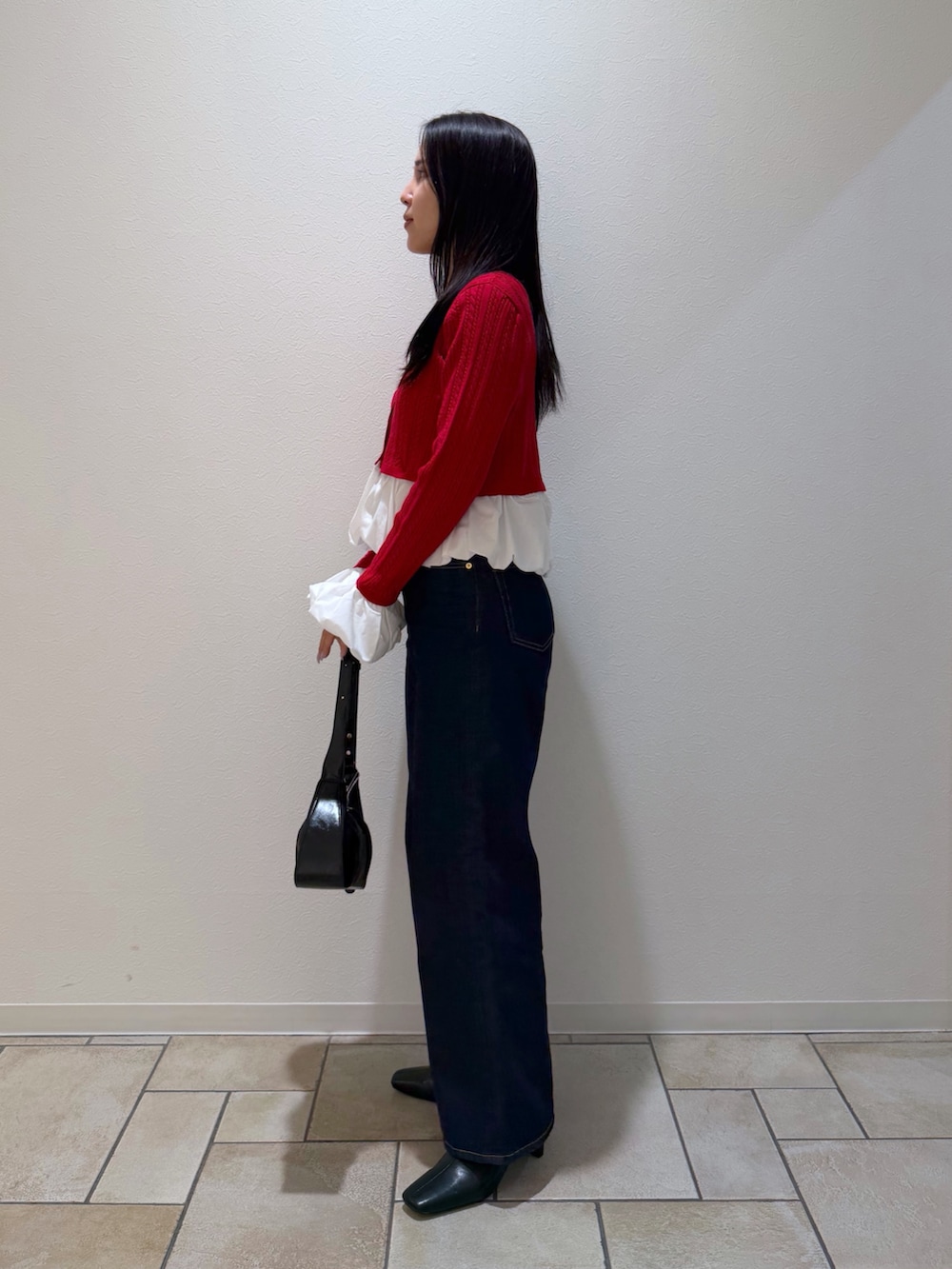 レッド系のカーディガン/ボレロ、ブルー系のデニムパンツ、ブラック系のブーツを着用したレディースの秋コーディネートの2枚目の写真