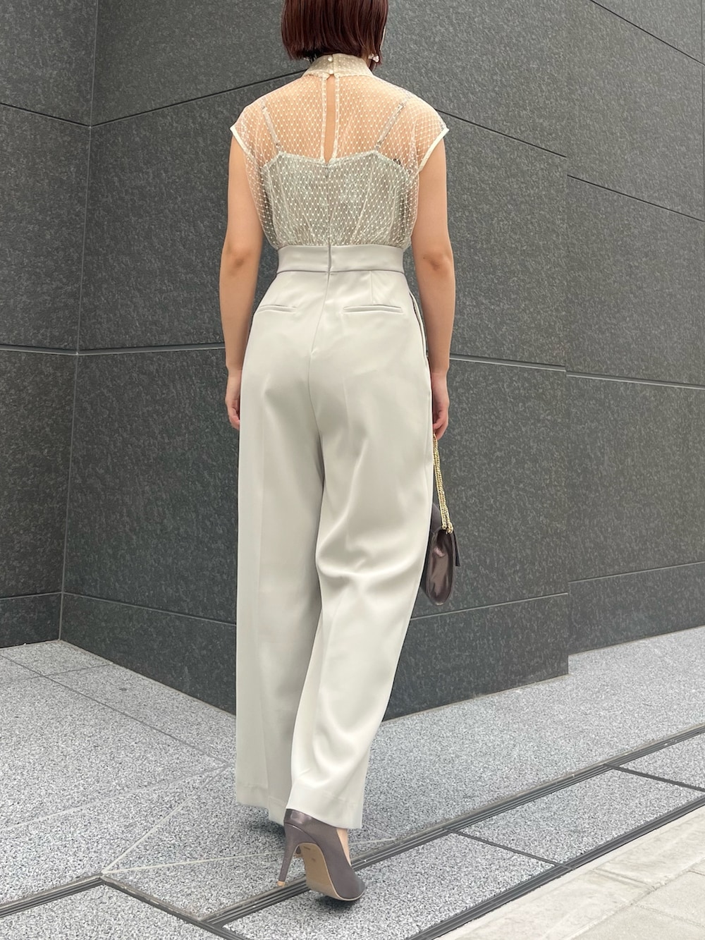 シルバー系のハンドバッグ、シルバー系のパンプス、グリーン系のパンツドレスを着用したレディースの春コーディネートの4枚目の写真