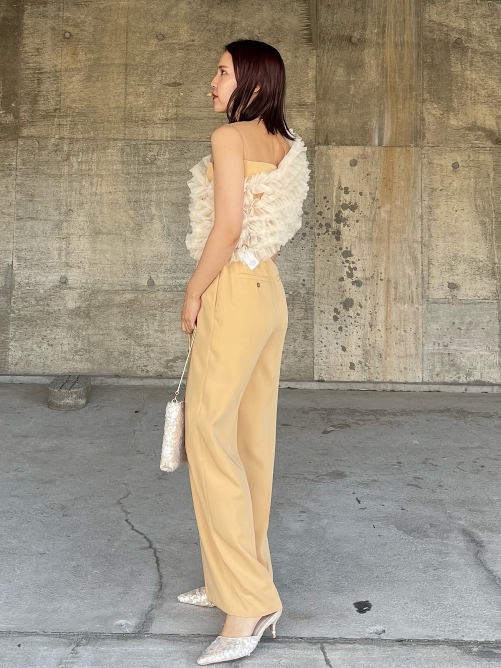 イエロー系のパンツドレス、ベージュ系のショルダーバッグ、ベージュ系のパンプスを着用したレディースの春コーディネートの5枚目の写真