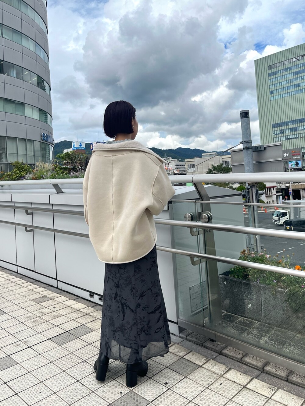 ホワイト系のムートンコート、グリーン系のニット/セーター、グレー系のスカートを着用したレディースの秋コーディネートの4枚目の写真