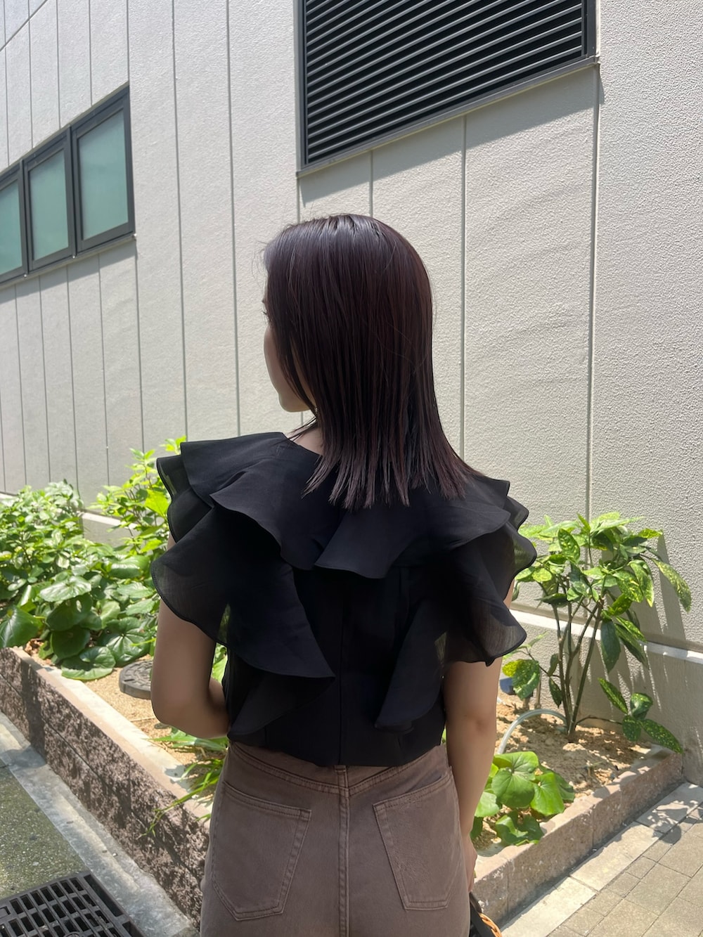 ベージュ系のデニムパンツ、ブラウン系のハンドバッグ、ブラック系のシャツ/ブラウスを着用したレディースの夏コーディネートの5枚目の写真