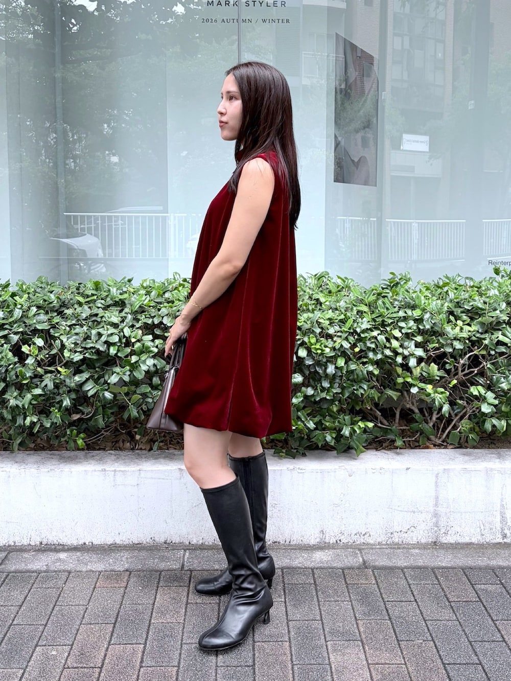 レッド系のワンピース、ブラック系のブーツを着用したレディースの秋コーディネートの2枚目の写真