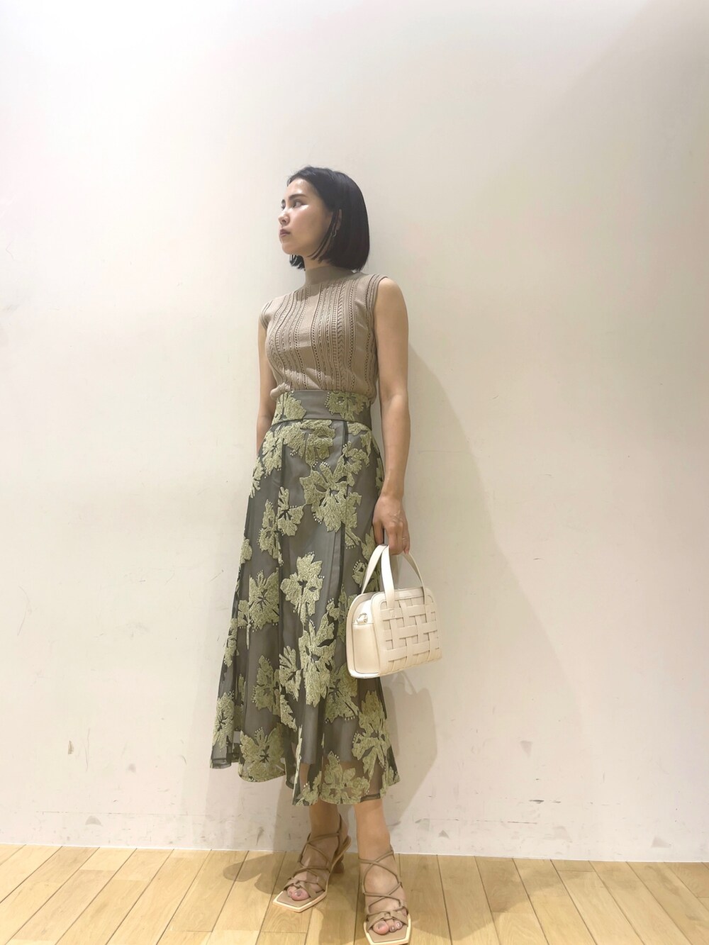 ベージュ系のニット/セーター、グリーン系のスカート、ベージュ系のサンダルを着用したレディースの夏コーディネートの2枚目の写真