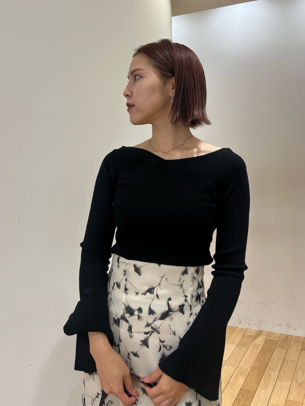 レッド系のショルダーバッグ、ホワイト系のスカート、シルバー系のブーツを着用したレディースの秋コーディネートの6枚目の写真