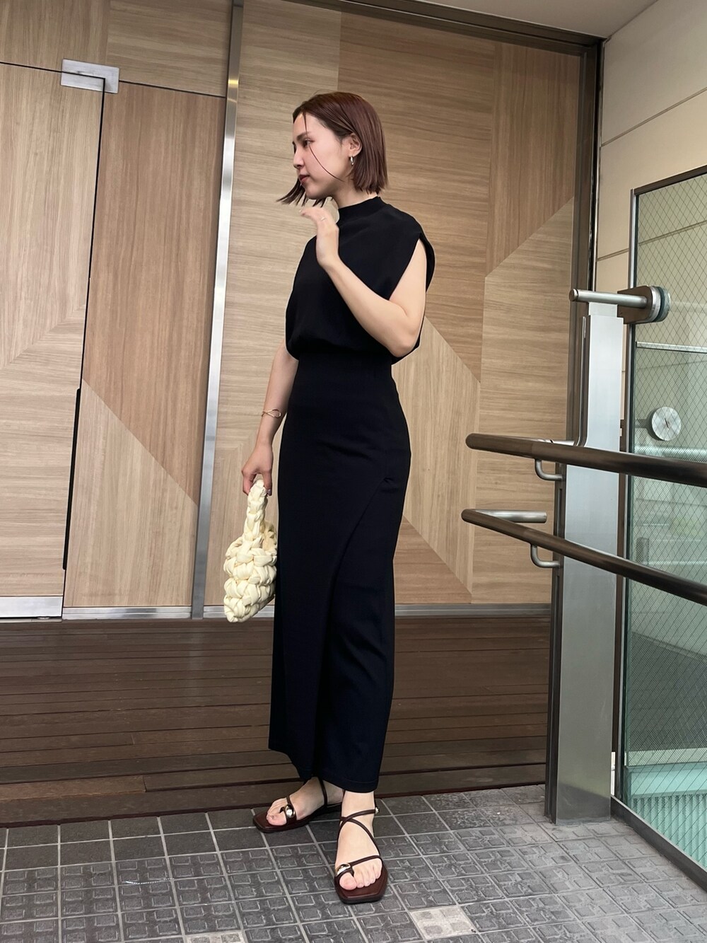 ブラック系のサンダル、ホワイト系のハンドバッグ、ブラック系のニット/セーターを着用したレディースの夏コーディネートの2枚目の写真