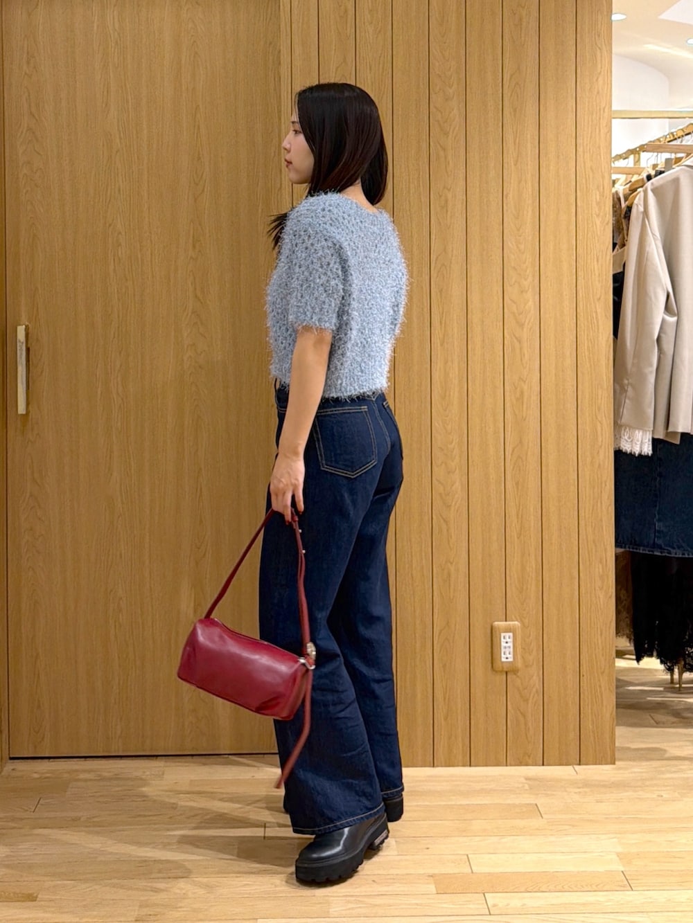 ブルー系のデニムパンツ、レッド系のハンドバッグ、ブルー系のニット/セーターを着用したレディースの秋コーディネートの2枚目の写真