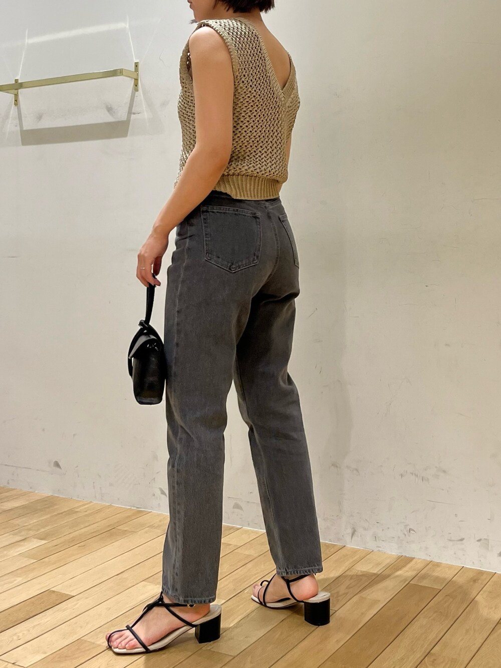 ブラック系のサンダル、ゴールド系のニット/セーター、ブラック系のハンドバッグを着用したレディースの夏コーディネートの4枚目の写真