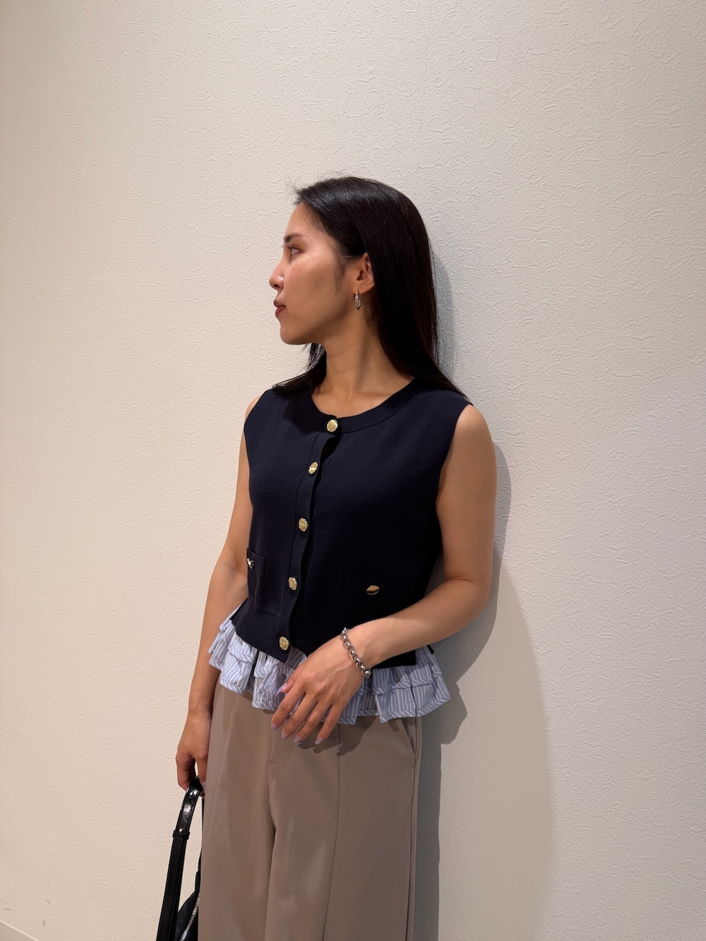 ベージュ系のその他パンツ、ブルー系のニット/セーター、ブラック系のハンドバッグを着用したレディースの夏コーディネートの4枚目の写真