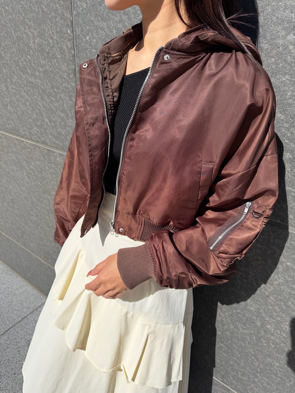 ブラック系のニット/セーター、ホワイト系のスカート、ブラウン系のブルゾンを着用したレディースの冬コーディネートの4枚目の写真