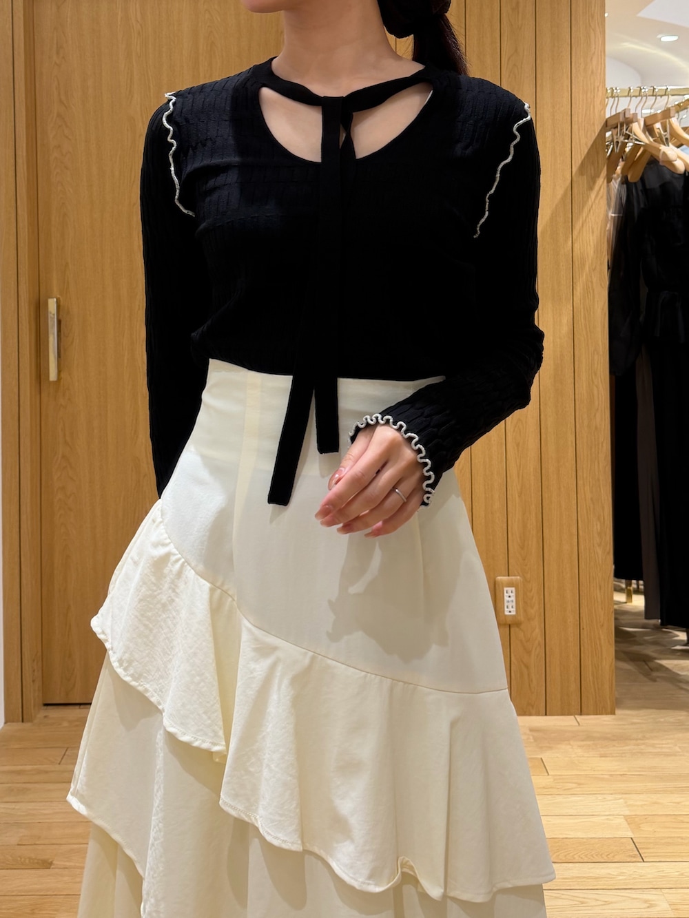 ブラック系のテーラードジャケット、ホワイト系のスカート、ブラック系のニット/セーターを着用したレディースの春コーディネートの6枚目の写真