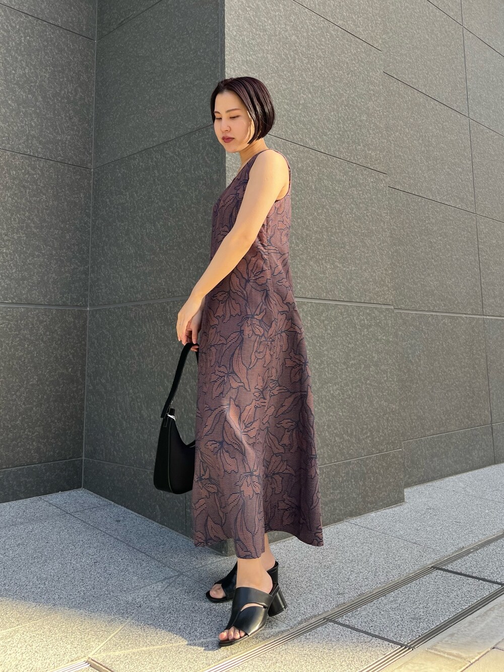 ブラック系のハンドバッグ、ブルー系のワンピース、ブラック系のサンダルを着用したレディースの春コーディネートの6枚目の写真