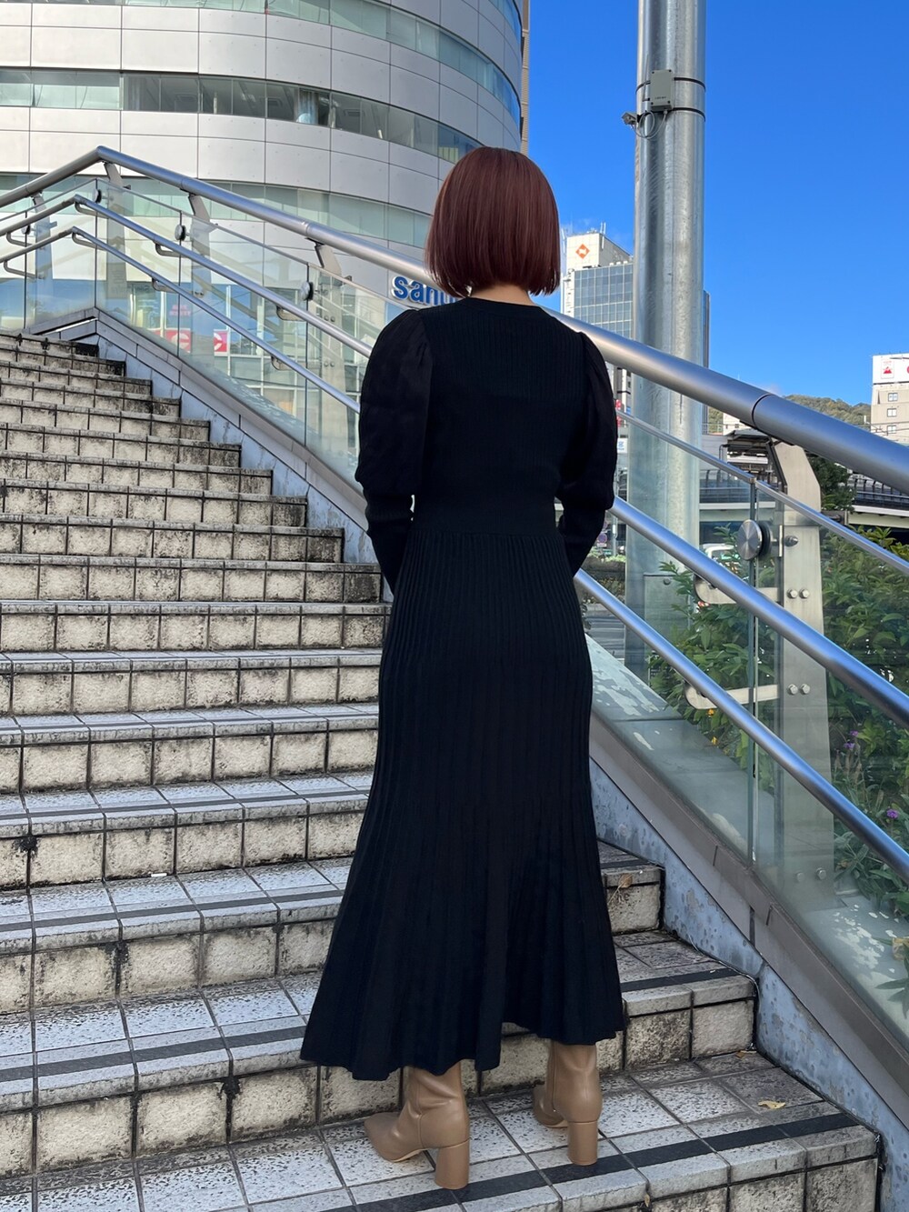 ブラック系のワンピース、ブラック系のハンドバッグ、ベージュ系のブーツを着用したレディースの秋コーディネートの3枚目の写真