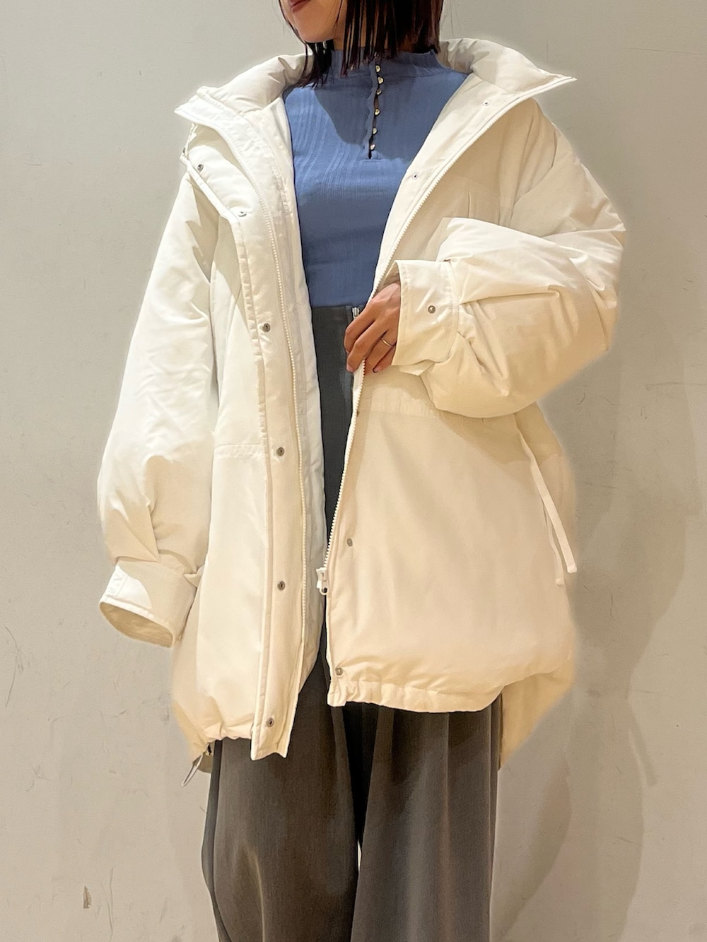 ブルー系のニット/セーター、グレー系のその他パンツ、ホワイト系のダウンジャケット/コートを着用したレディースの冬コーディネートの4枚目の写真