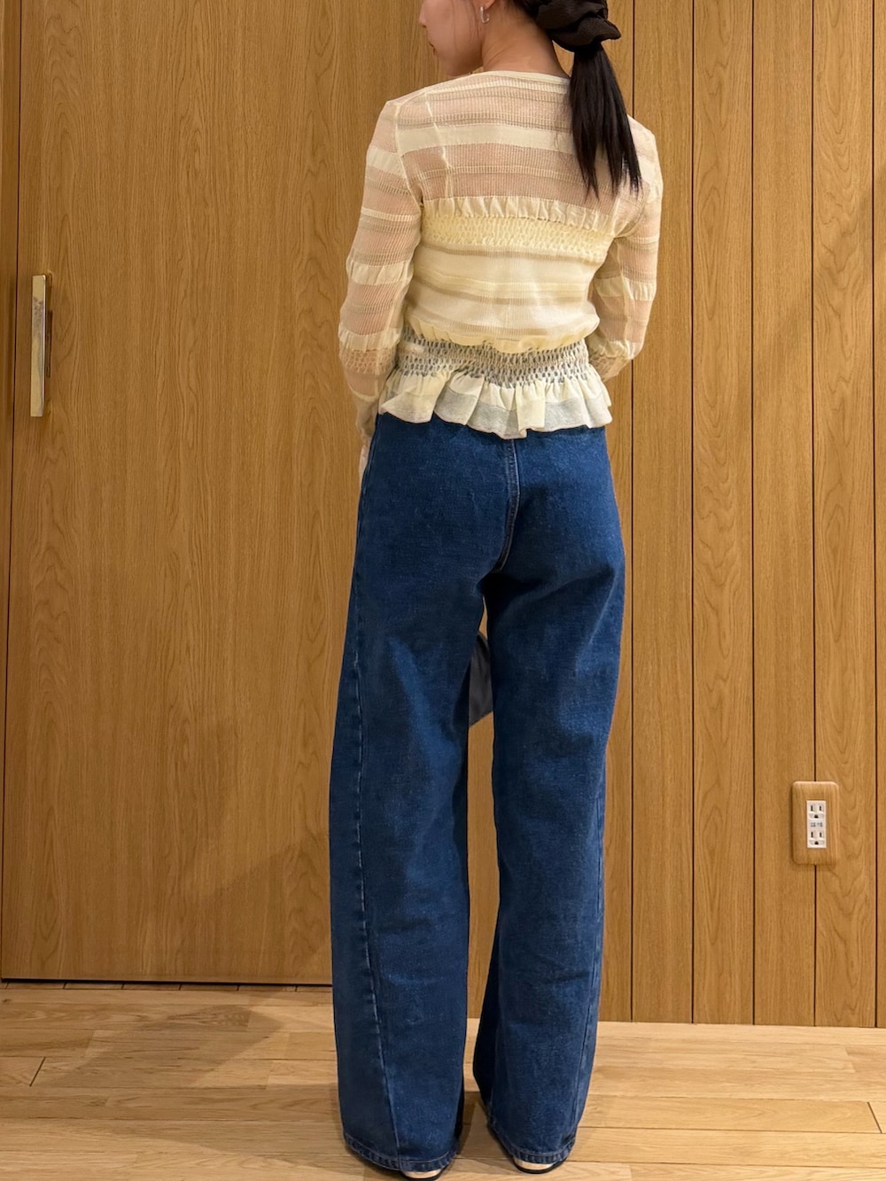 ブルー系のデニムパンツ、ブラック系のハンドバッグ、ホワイト系のニット/セーターを着用したレディースの春コーディネートの3枚目の写真