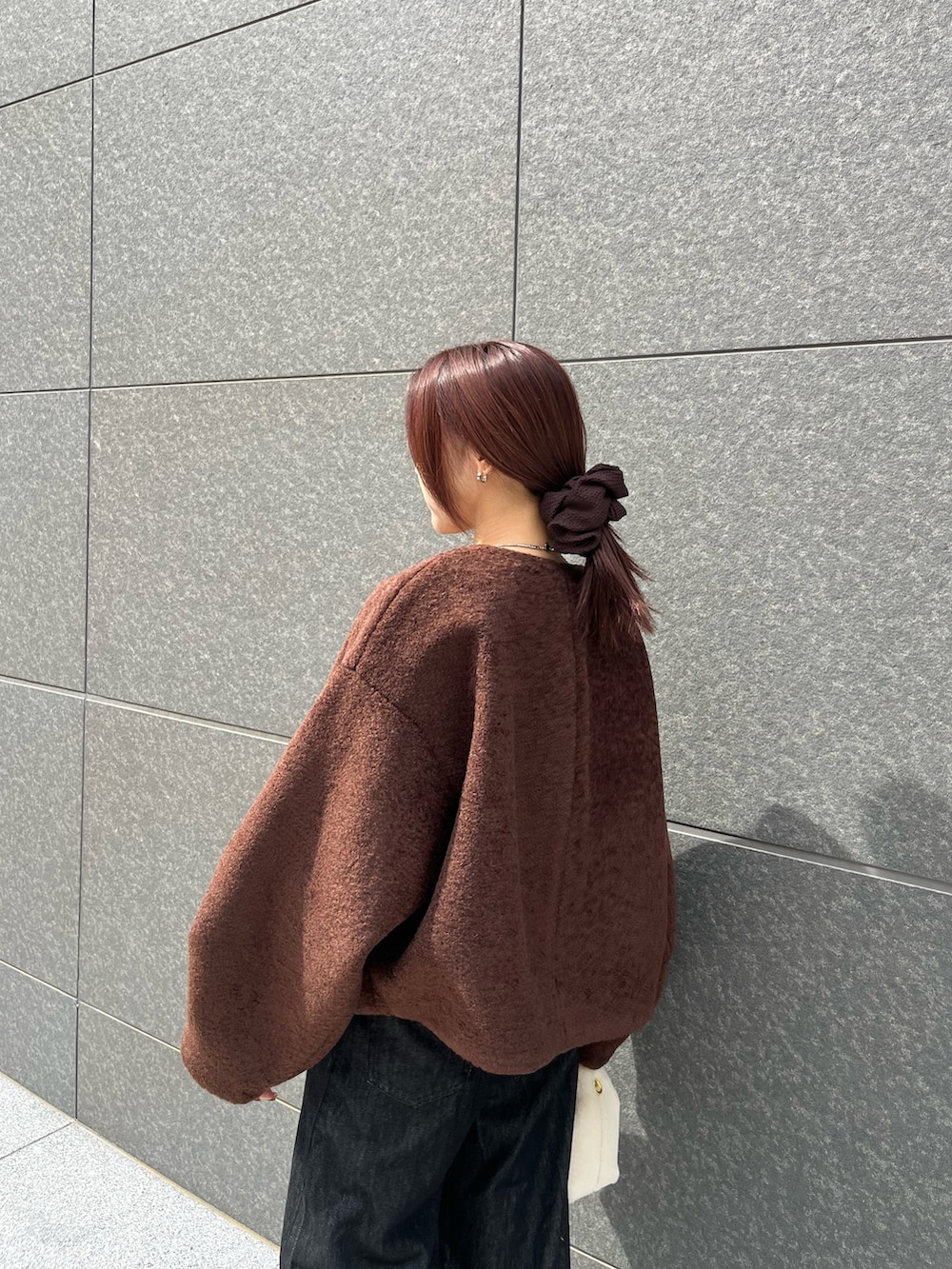 ブラック系のデニムパンツ、ホワイト系のハンドバッグ、ブラウン系のTシャツ/カットソーを着用したレディースの秋コーディネートの5枚目の写真