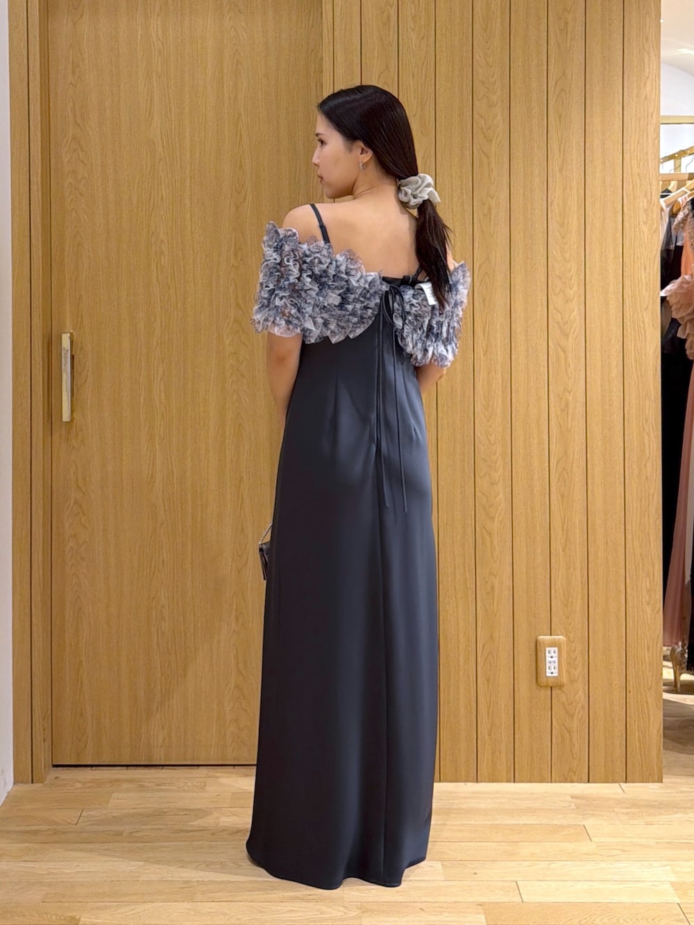 グレー系のドレス、シルバー系のクラッチバッグ、ゴールド系のパンプスを着用したレディースの秋コーディネートの3枚目の写真