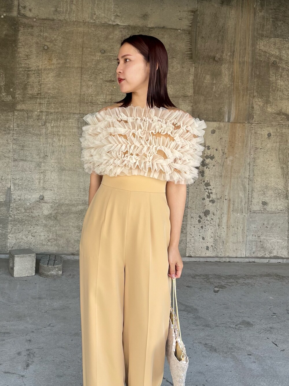 イエロー系のパンツドレス、ベージュ系のショルダーバッグ、ベージュ系のパンプスを着用したレディースの春コーディネートの6枚目の写真