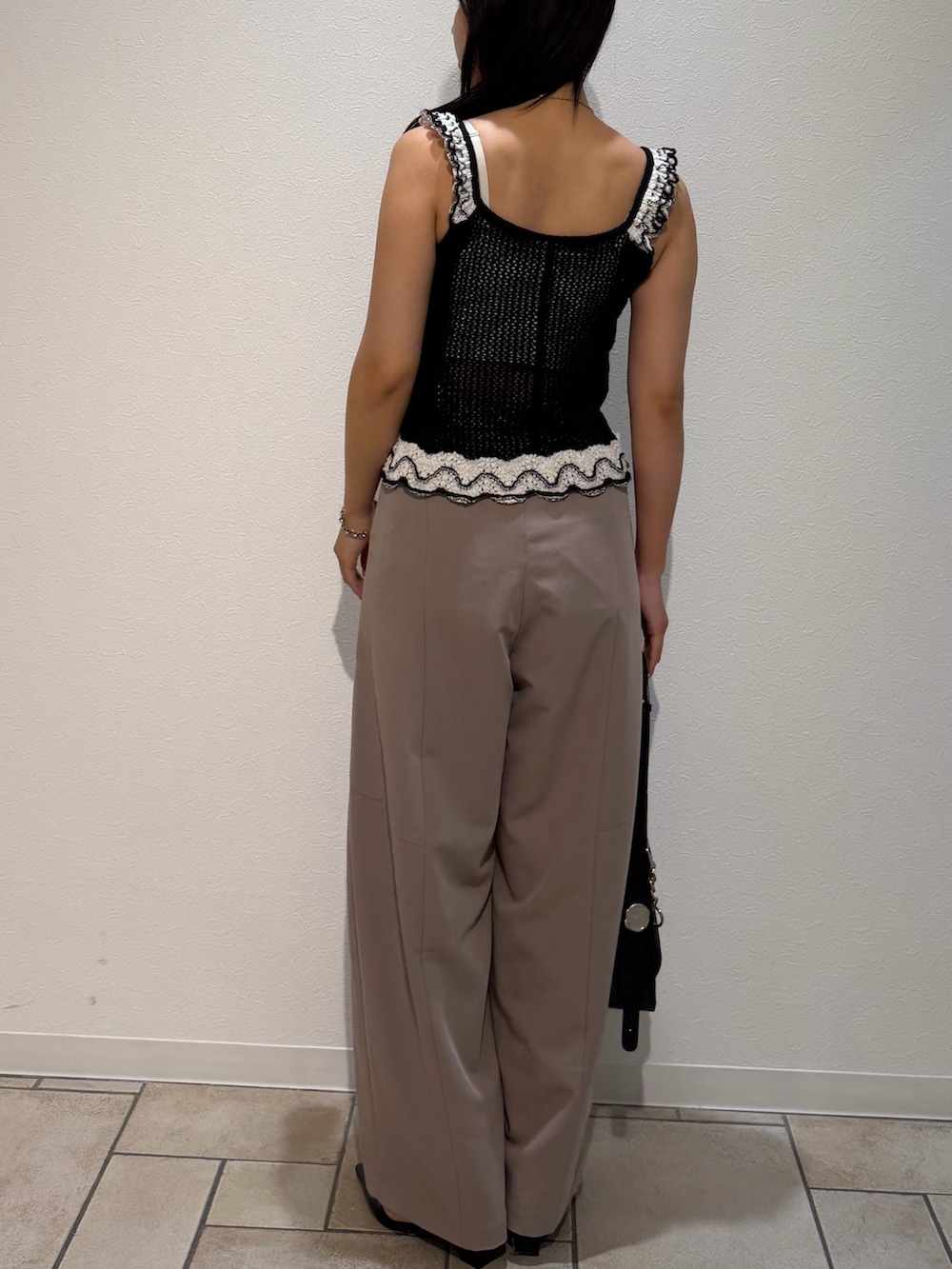 ベージュ系のその他パンツ、ブラック系のニット/セーター、ブラック系のハンドバッグを着用したレディースの夏コーディネートの3枚目の写真