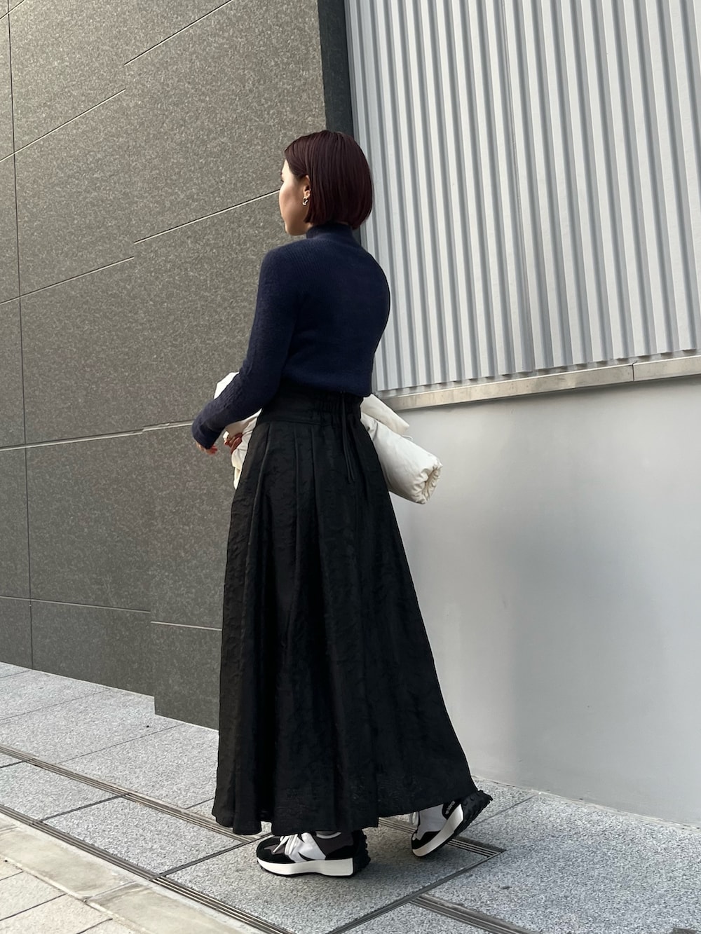 ホワイト系のダウンジャケット/コート、ブルー系のニット/セーター、ブラック系のスカートを着用したレディースの冬コーディネートの3枚目の写真