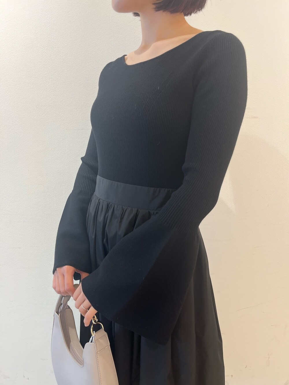 ブラック系のワンピース、ホワイト系のハンドバッグ、ブラック系のパンプスを着用したレディースの秋コーディネートの7枚目の写真