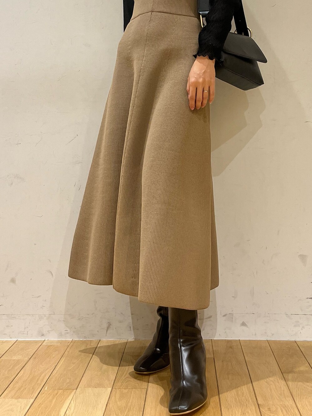 ブラック系のブーツ、ブラウン系のジャンパースカート、ブラック系のショルダーバッグを着用したレディースの秋コーディネートの6枚目の写真