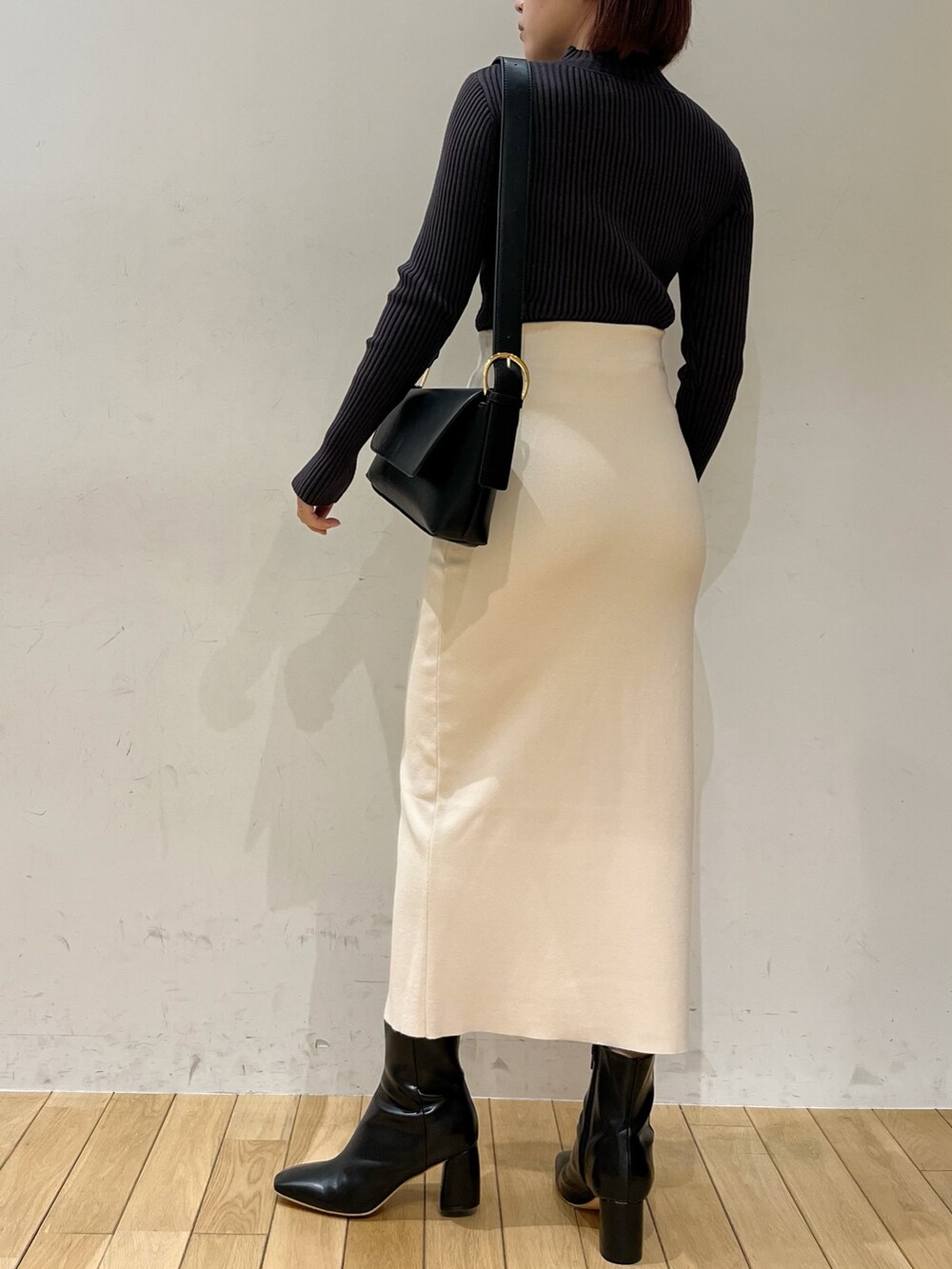 グレー系のニット/セーター、ブラック系のショルダーバッグ、ブラック系のブーツを着用したレディースの冬コーディネートの4枚目の写真