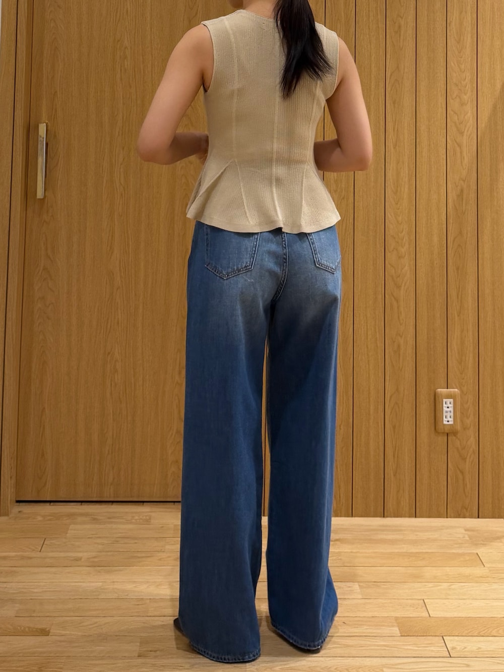ブルー系のデニムパンツ、ベージュ系のニット/セーター、ブラウン系のサンダルを着用したレディースの夏コーディネートの3枚目の写真