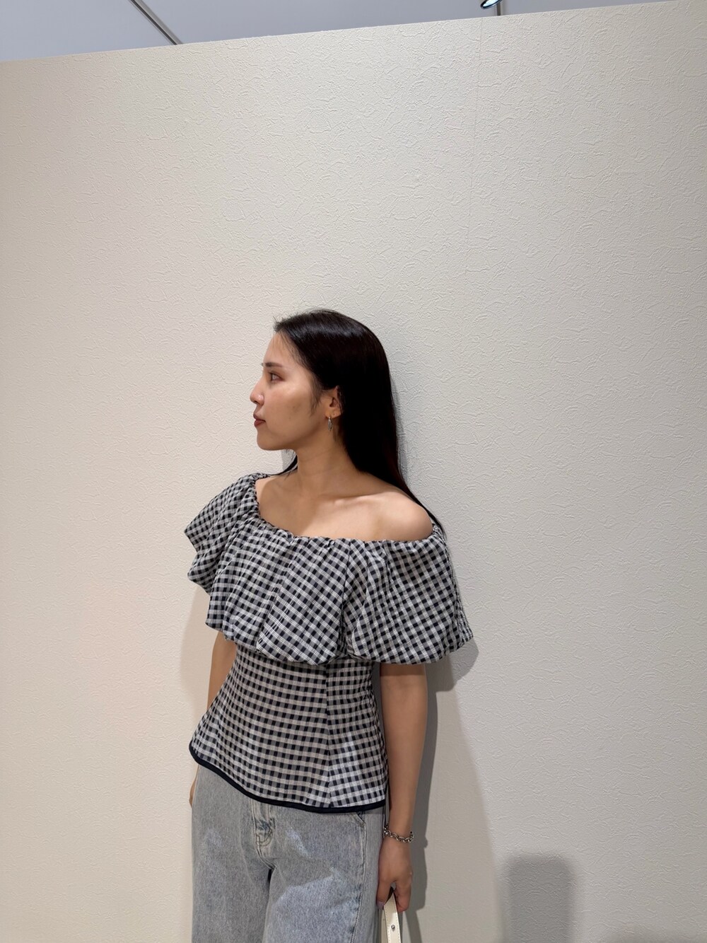 ブルー系のデニムパンツ、ホワイト系のサンダル、ホワイト系のハンドバッグを着用したレディースの夏コーディネートの4枚目の写真
