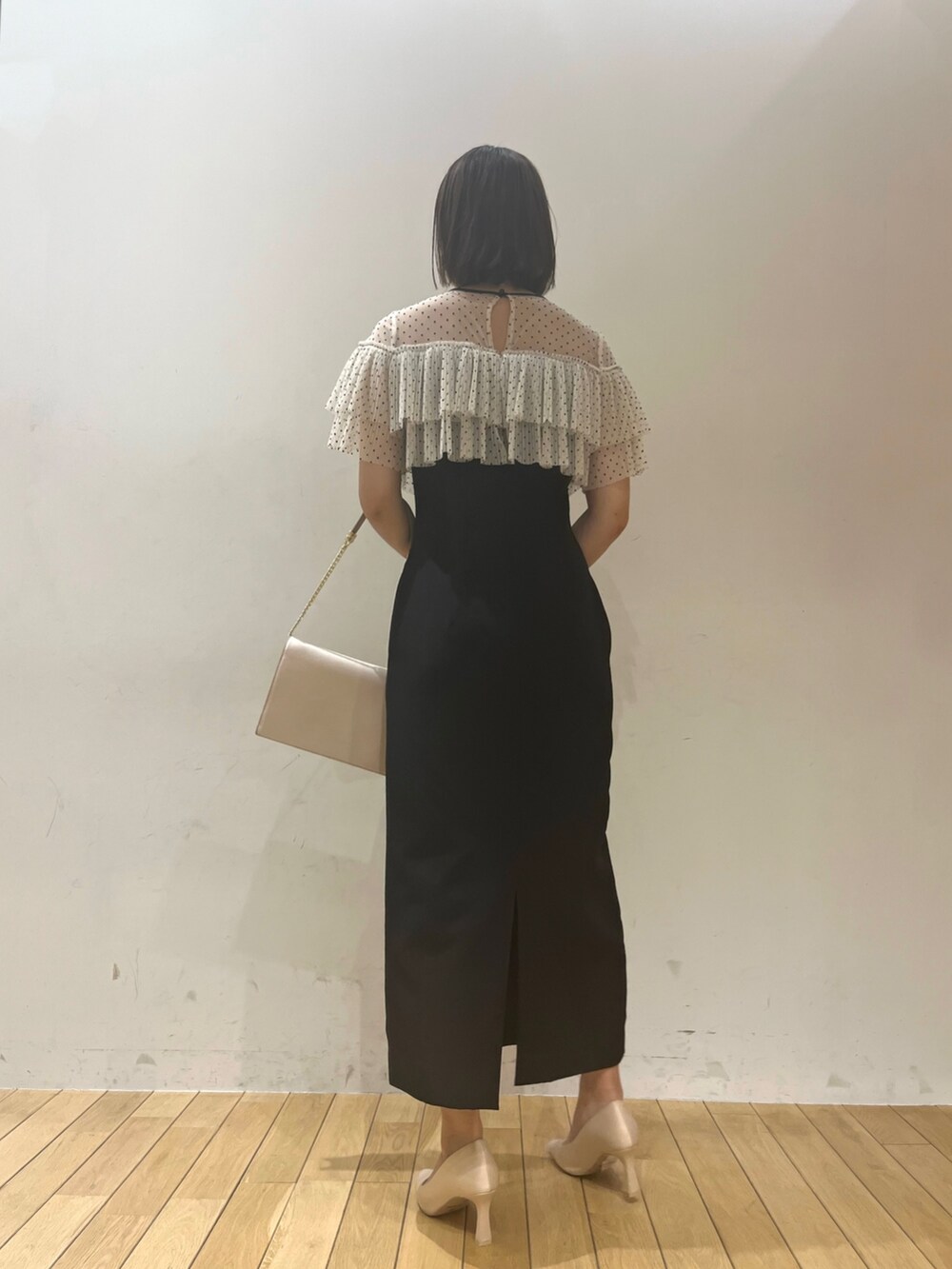 ブラウン系のパンプス、ブラウン系のクラッチバッグ、ブラック系のドレスを着用したレディースの春コーディネートの4枚目の写真
