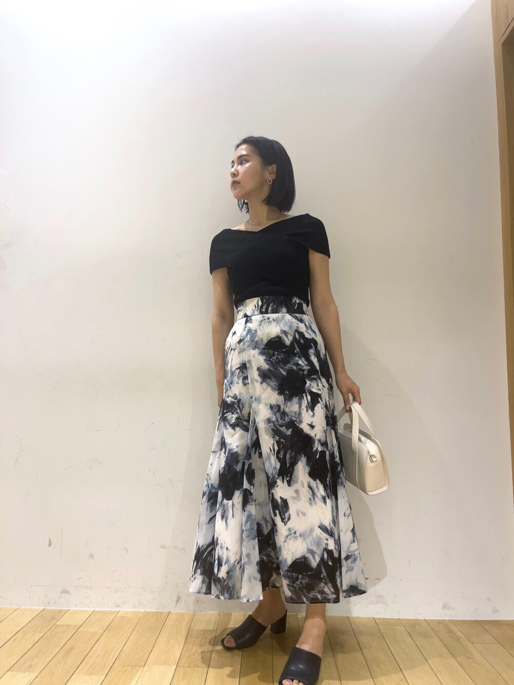 ブラック系のニット/セーター、ブルー系のサンダル、ホワイト系のショルダーバッグを着用したレディースの夏コーディネートの2枚目の写真