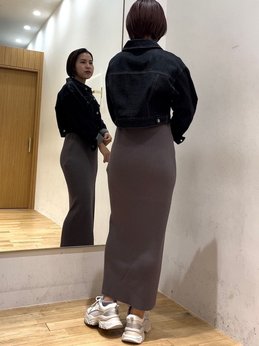 ブラック系のデニムジャケット、グレー系のワンピースを着用したレディースの冬コーディネートの2枚目の写真