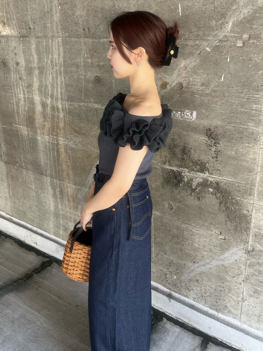 グレー系のニット/セーター、ブラウン系のハンドバッグ、ブルー系のデニムパンツを着用したレディースの夏コーディネートの5枚目の写真