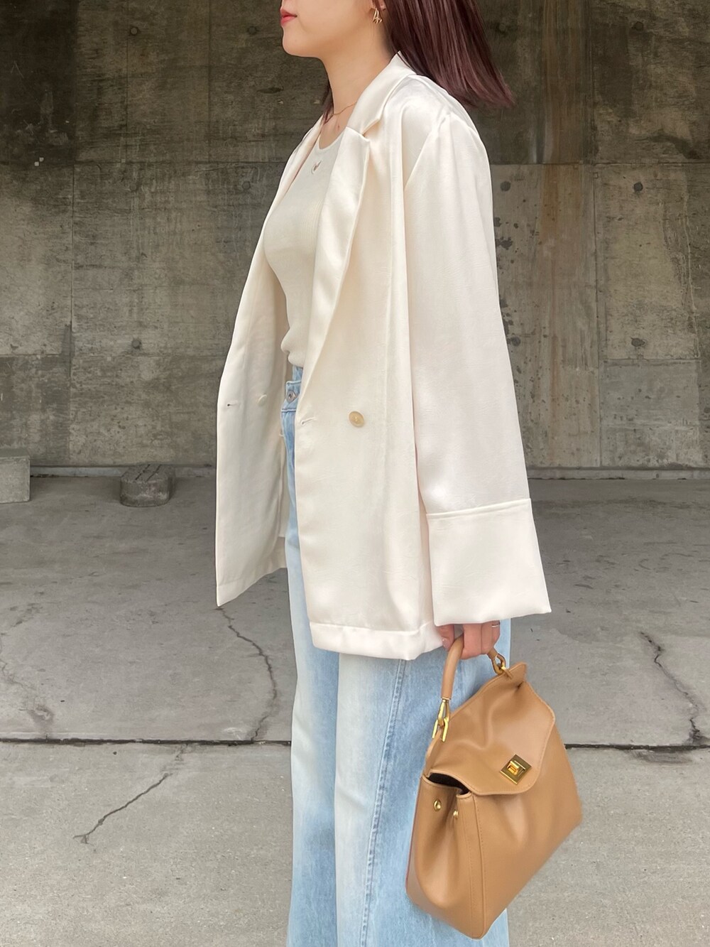 ブルー系のデニムパンツ、シルバー系のサンダル、ブラウン系のハンドバッグを着用したレディースの春コーディネートの5枚目の写真