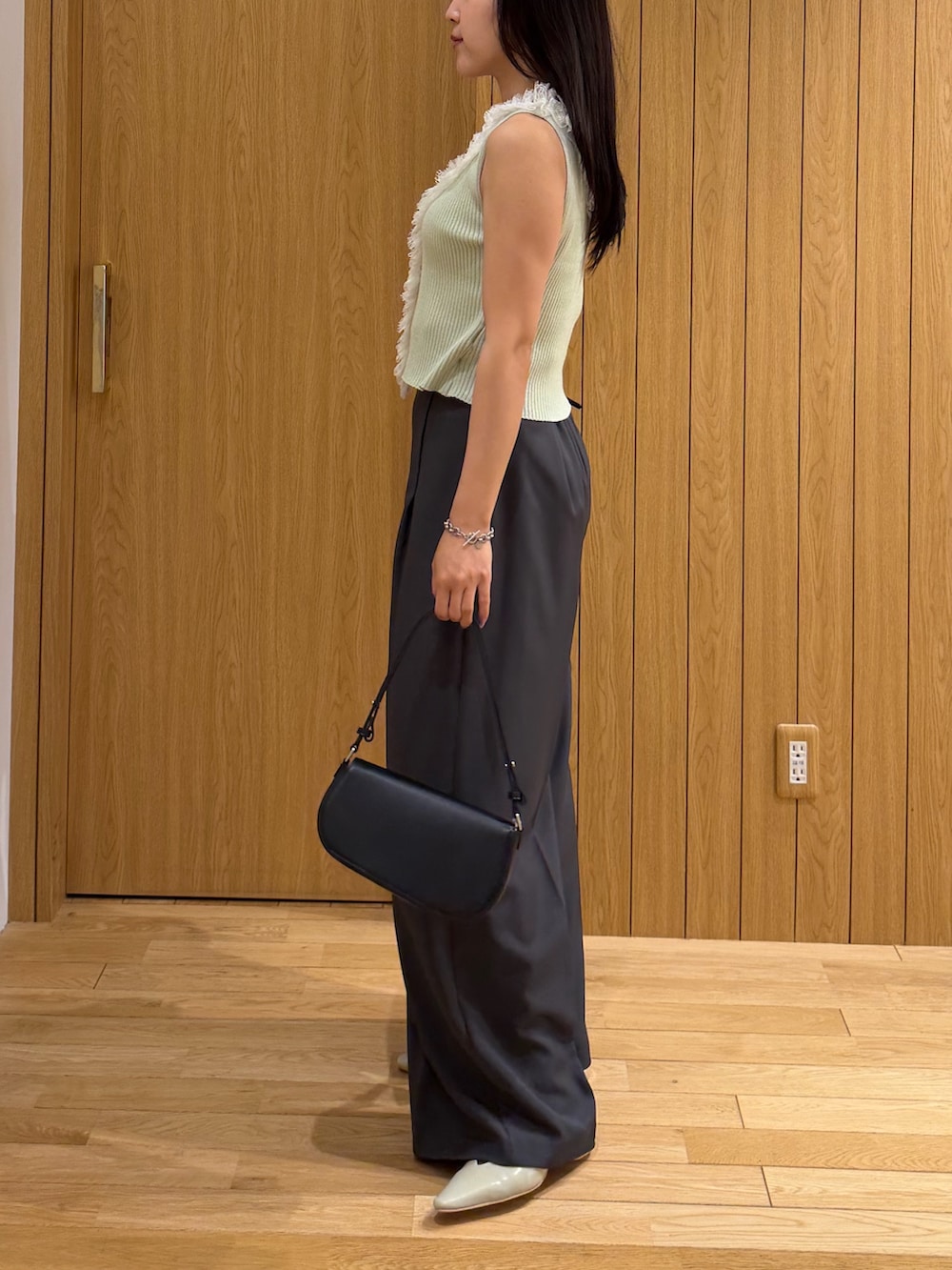 グレー系のその他パンツ、ブラック系のハンドバッグ、グリーン系のニット/セーターを着用したレディースの夏コーディネートの2枚目の写真