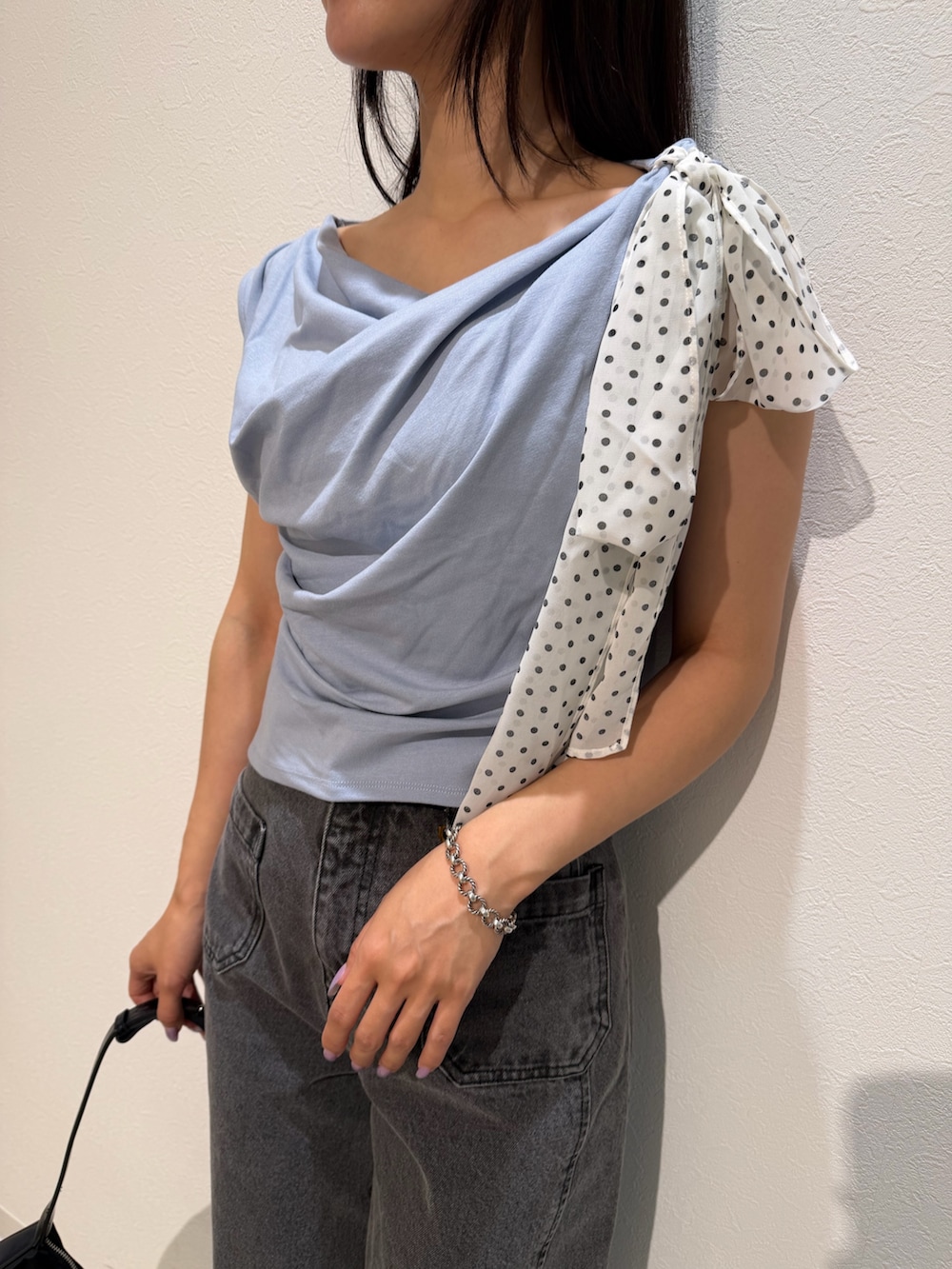 ブラック系のデニムパンツ、ブラック系のハンドバッグ、ブルー系のTシャツ/カットソーを着用したレディースの夏コーディネートの7枚目の写真