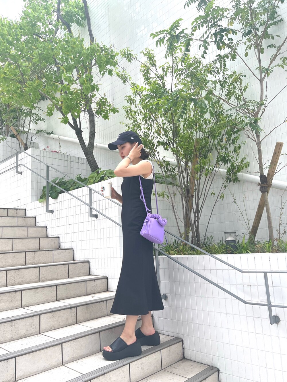 ブラック系のワンピース、ホワイト系のニット/セーター、パープル系のハンドバッグを着用したレディースの夏コーディネートの3枚目の写真