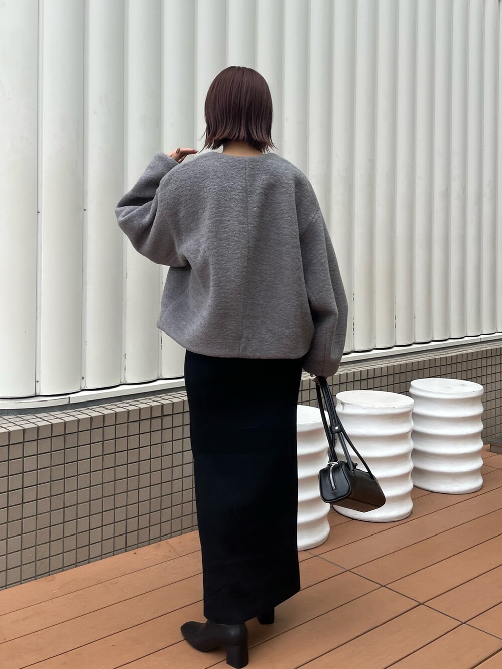 グレー系のブルゾン、ホワイト系のTシャツ/カットソー、ブラック系のショルダーバッグを着用したレディースの秋コーディネートの3枚目の写真