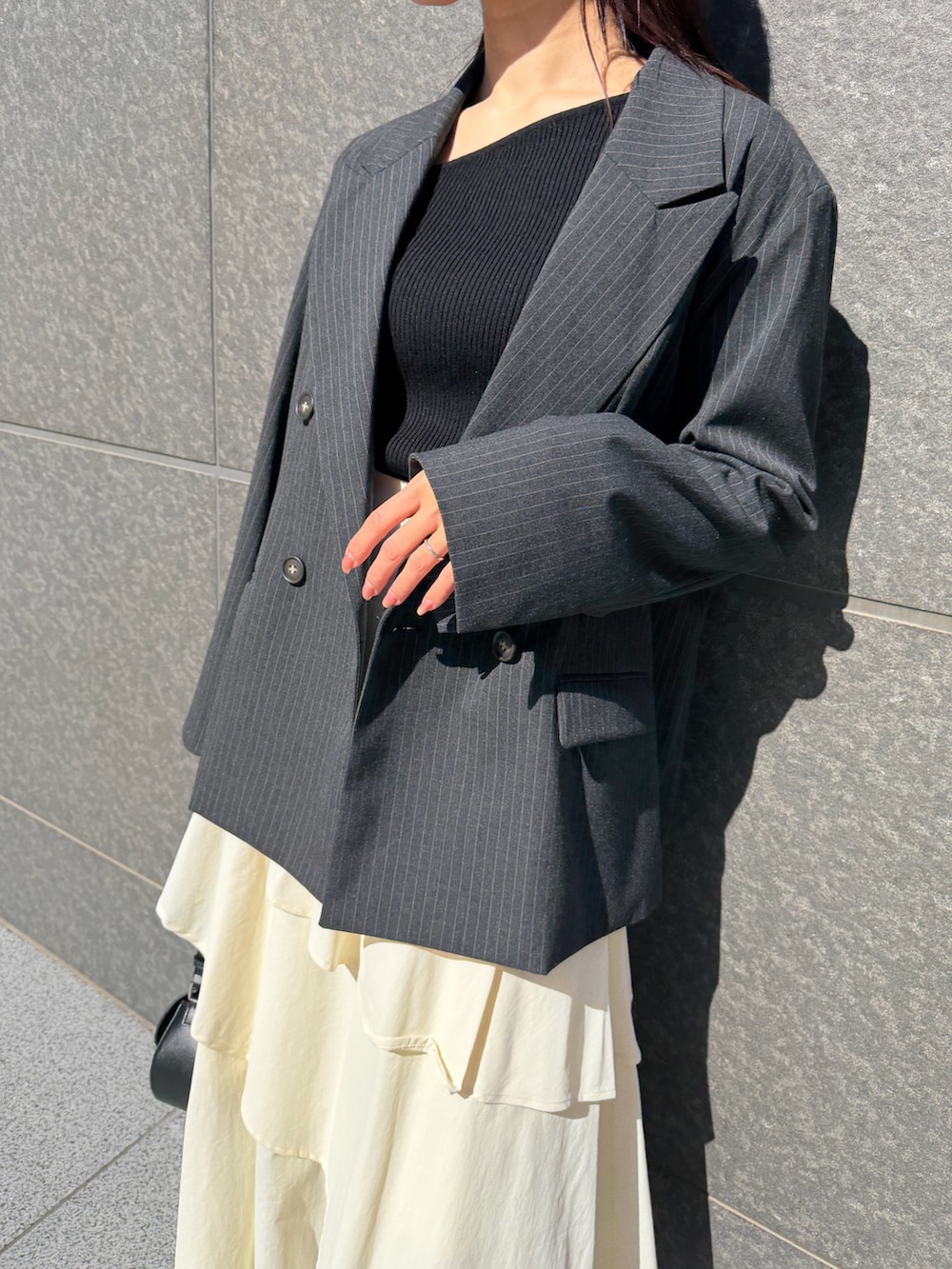 ホワイト系のスカート、ブラック系のニット/セーター、ブラック系のハンドバッグを着用したレディースの冬コーディネートの6枚目の写真