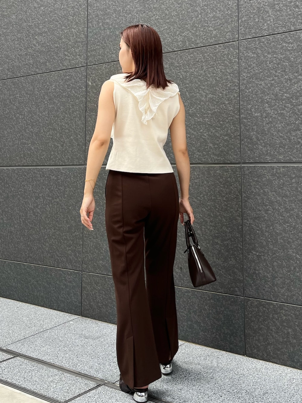 ホワイト系のニット/セーター、ブラウン系のその他パンツ、ブラウン系のボストンバッグを着用したレディースの夏コーディネートの3枚目の写真