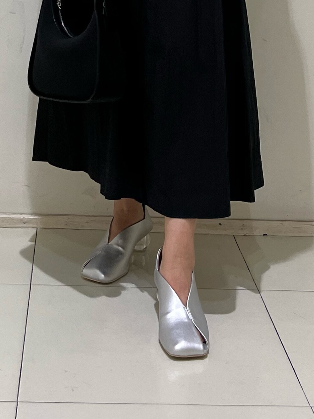 ブラック系のシャツワンピース、ブラック系のハンドバッグ、シルバー系のパンプスを着用したレディースの冬コーディネートの6枚目の写真