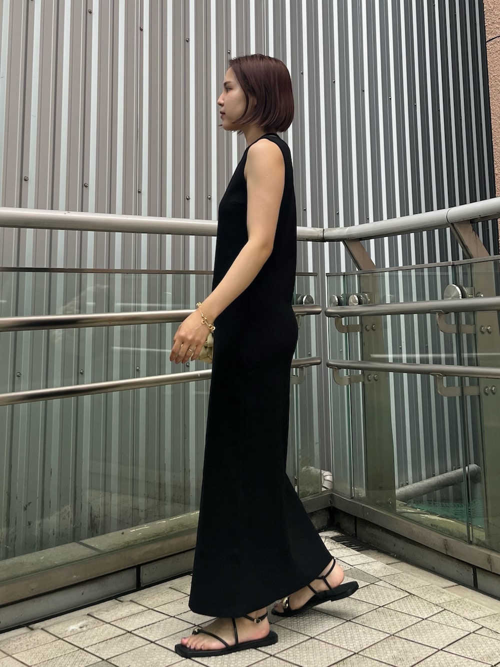 ブラック系のワンピース、ブラック系のサンダル、ホワイト系のハンドバッグを着用したレディースの夏コーディネートの2枚目の写真