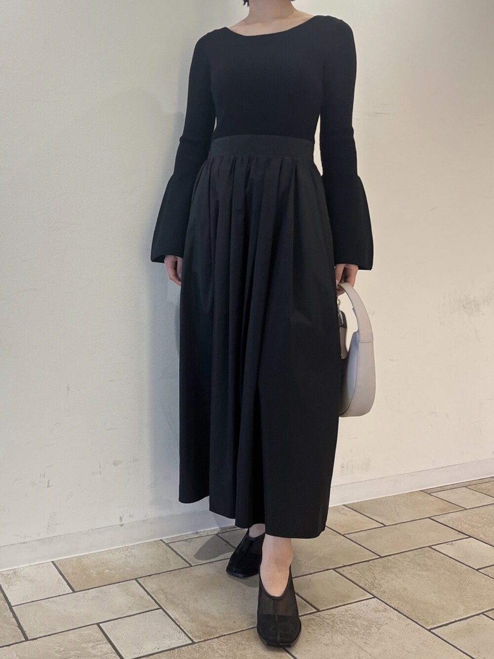 ブラック系のワンピース、ホワイト系のハンドバッグ、ブラック系のパンプスを着用したレディースの秋コーディネートの2枚目の写真