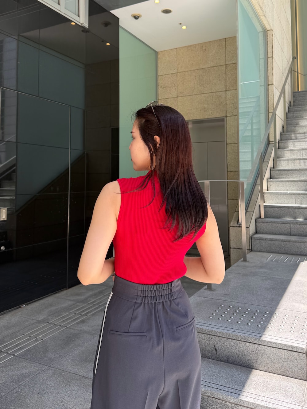 グレー系のその他パンツ、レッド系のニット/セーター、ブラウン系のハンドバッグを着用したレディースの春コーディネートの5枚目の写真