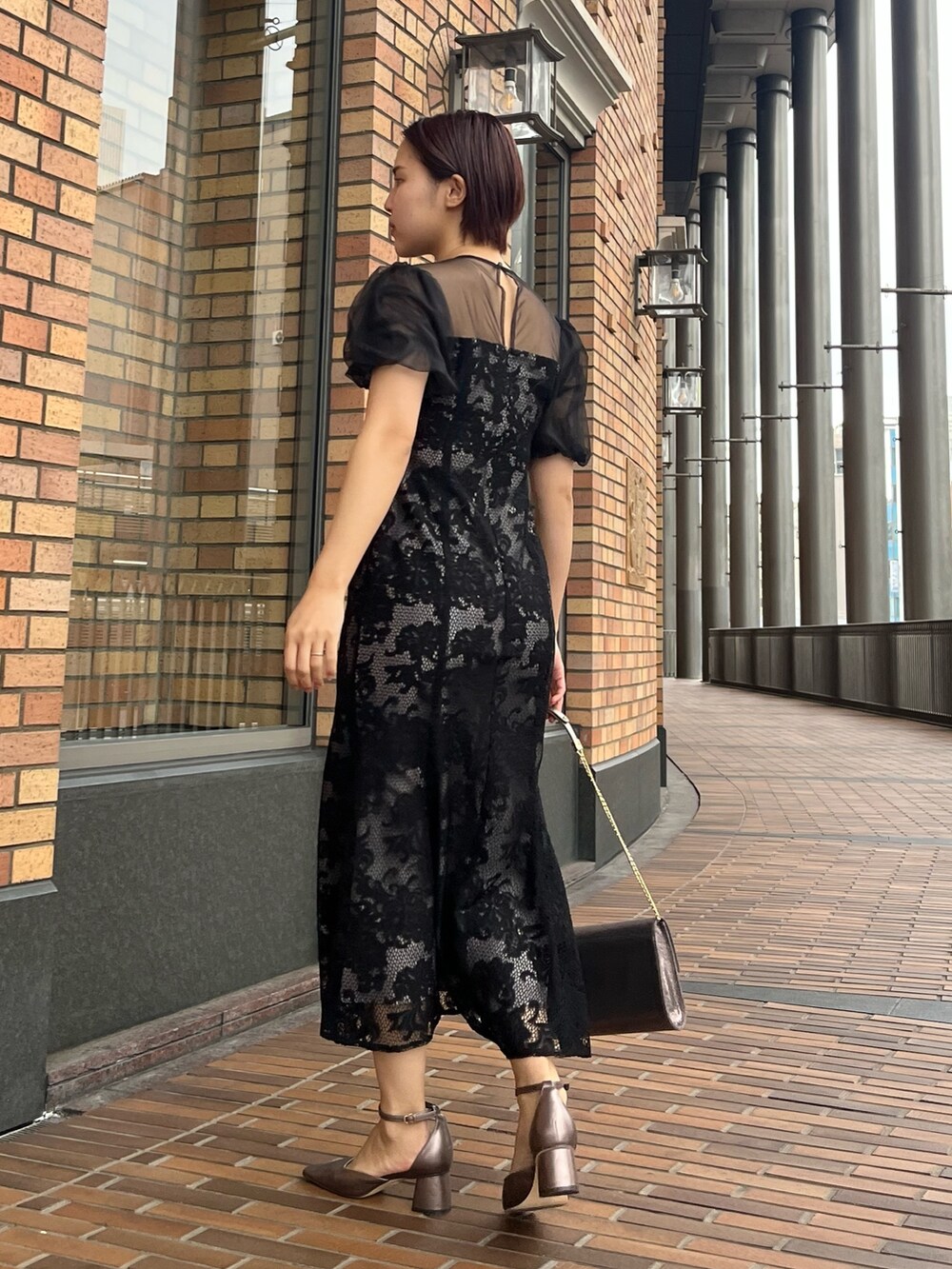 ブラック系のドレス、その他のパンプス、シルバー系のハンドバッグを着用したレディースの冬コーディネートの3枚目の写真