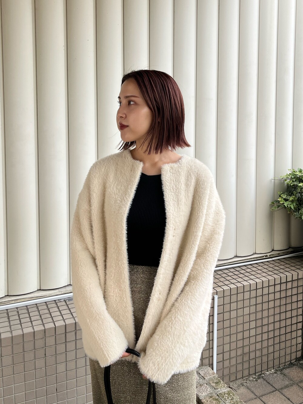 ホワイト系のカーディガン/ボレロ、ゴールド系のスカート、ブラック系のニット/セーターを着用したレディースの冬コーディネートの5枚目の写真